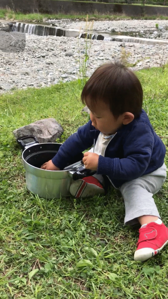野外で鍋に触れる子どもの様子（アウトドア炊飯）